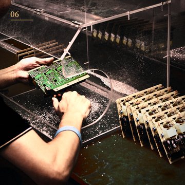 Hands holding an assembled circuit board on the production line