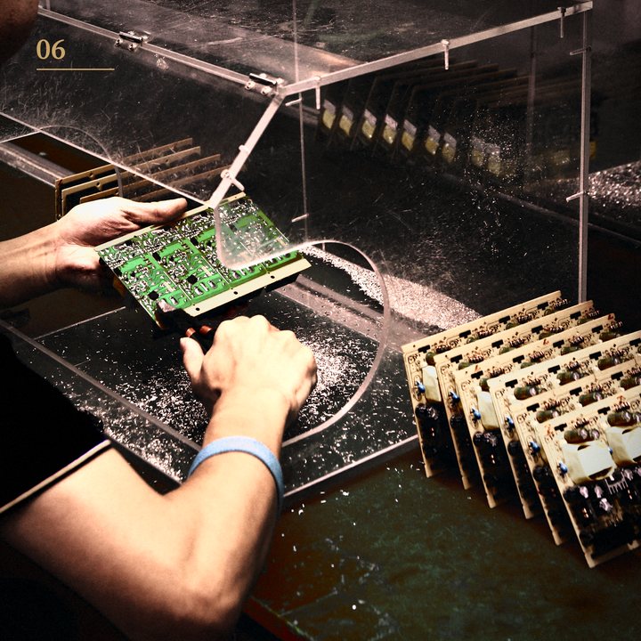 Hands holding an assembled circuit board on the production line