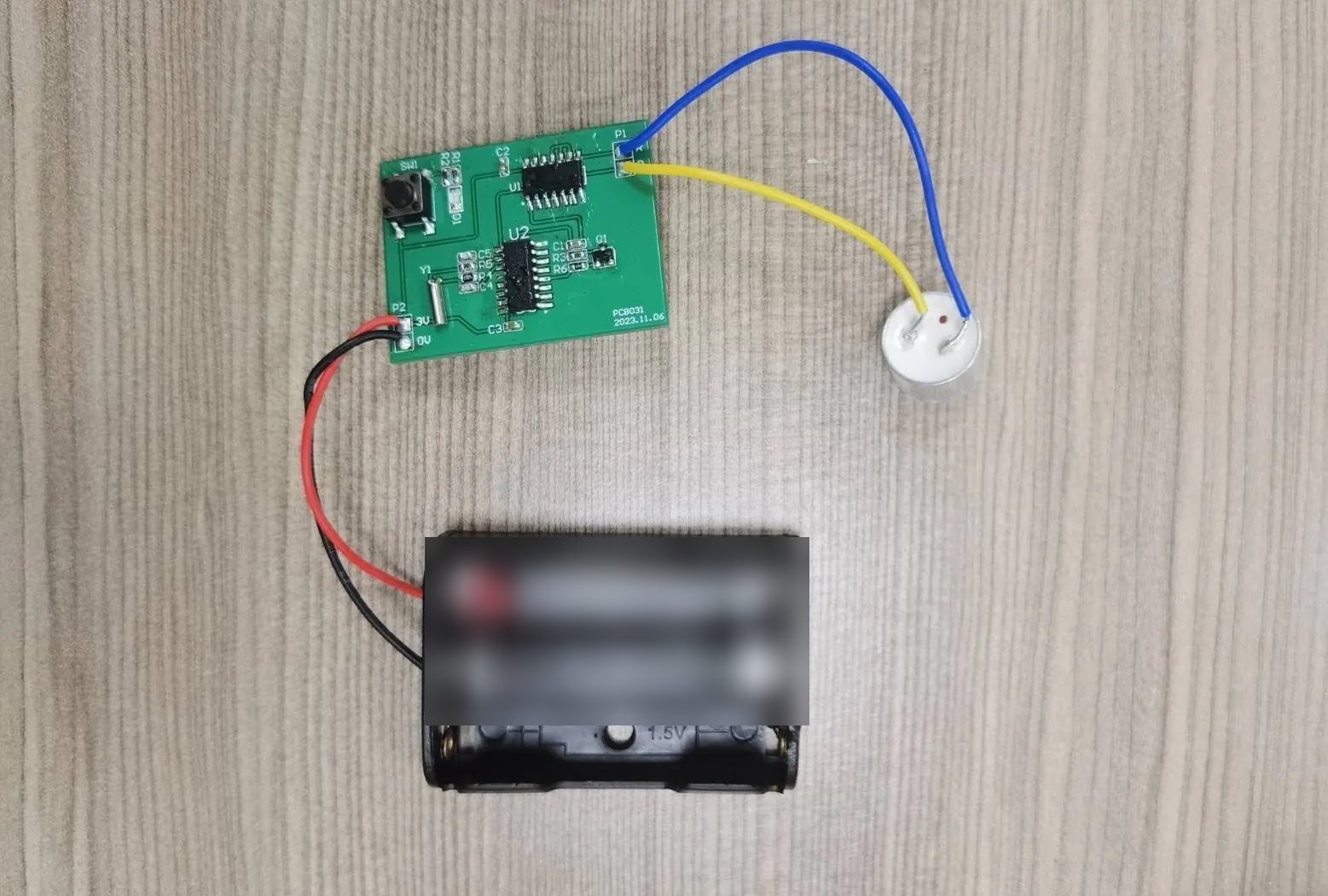 An assembled printed circuit board on functional test with a wiring harness and battery pack