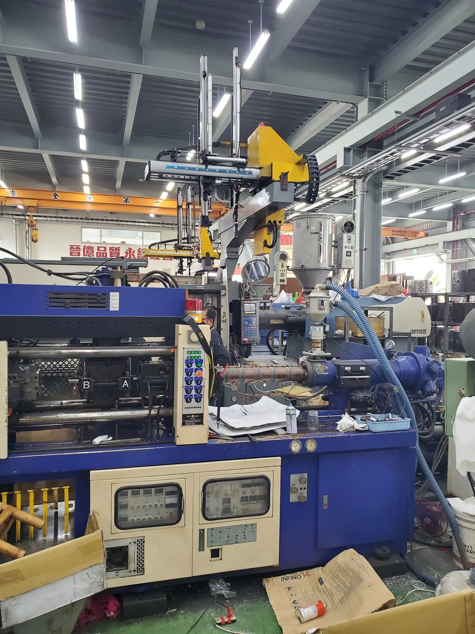 An injection molding machine mid-cycle producing plastic parts at a partner factory
