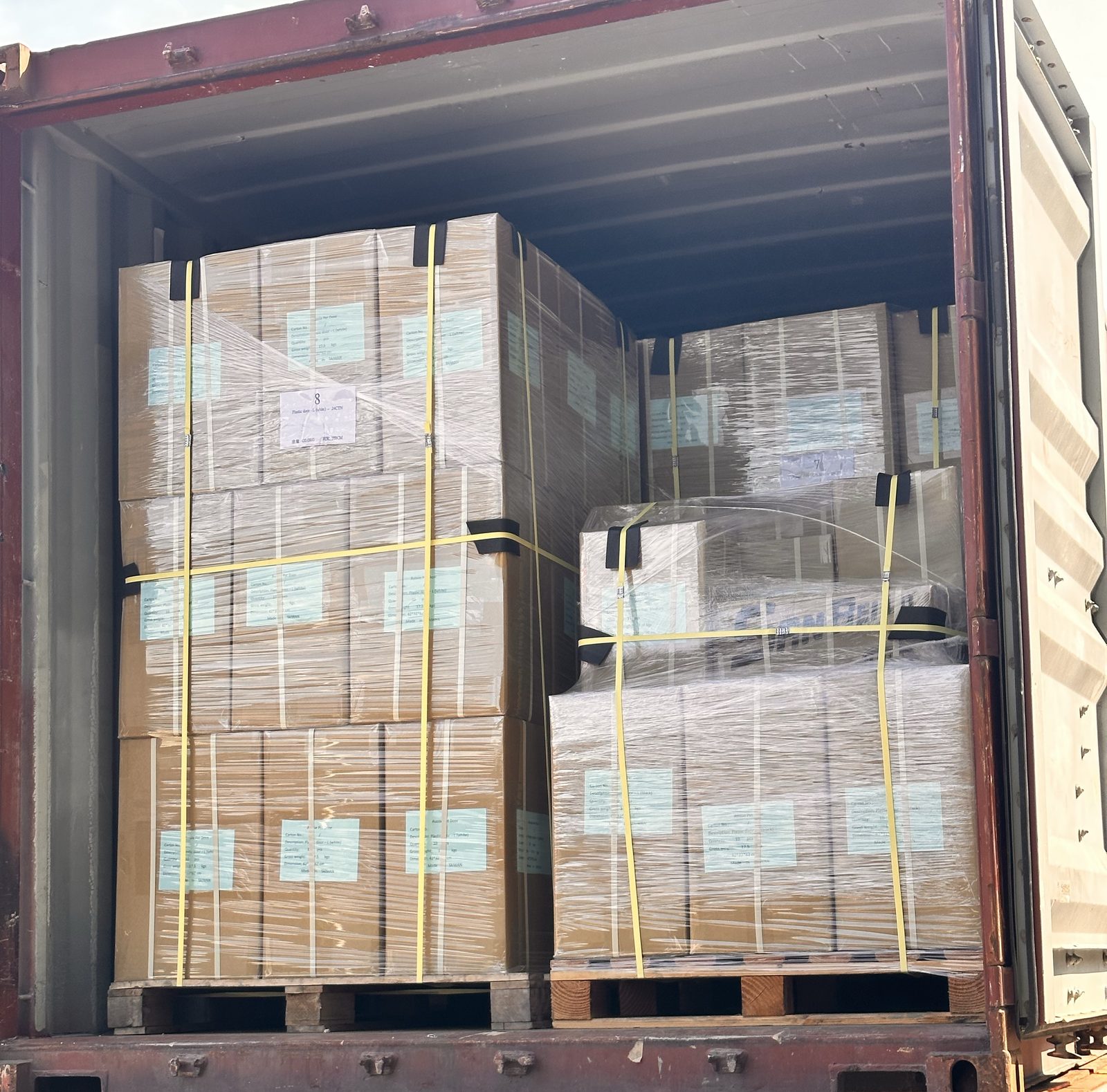 Shrink-wrapped, strapped pallets of cartons loaded into a shipping container on a trailer