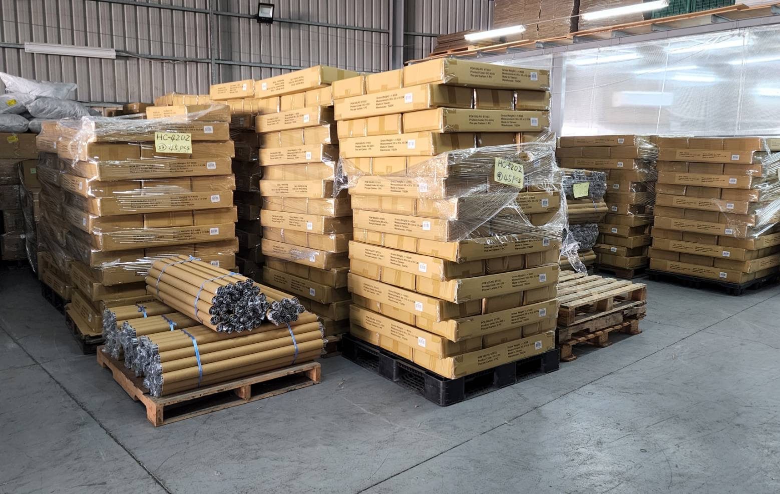 Palletized and stretch-wrapped export cartons with handwritten lot tags in a factory warehouse