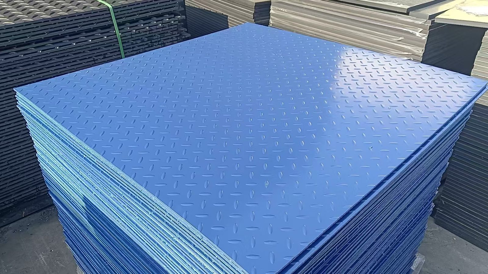 A tall stack of blue powder-coated tread plate panels, a finished production lot ready for packing