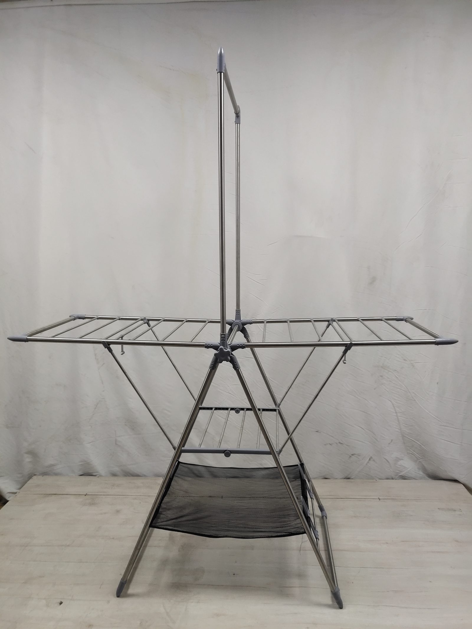 A stainless steel folding drying rack sample standing open on a table against a white backdrop