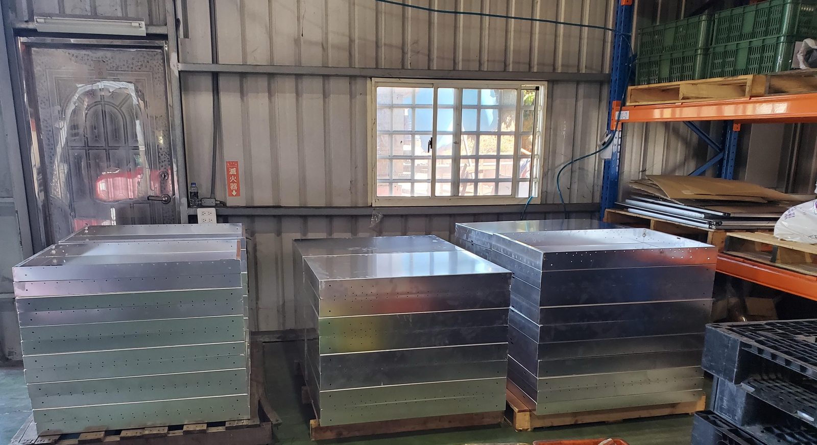 Finished stainless steel enclosures stacked on pallets, ready for inspection before the balance payment