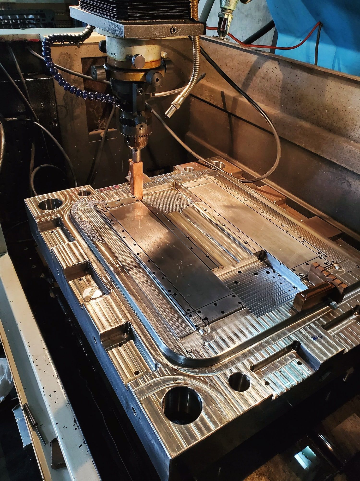 A machine cutting the cavity of an injection mold plate in tool steel, the plate clamped on the machine bed
