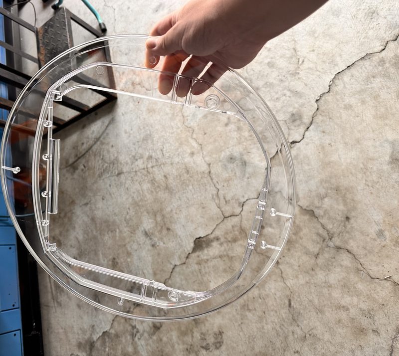 A clear molded plastic part held up as the sample to work from