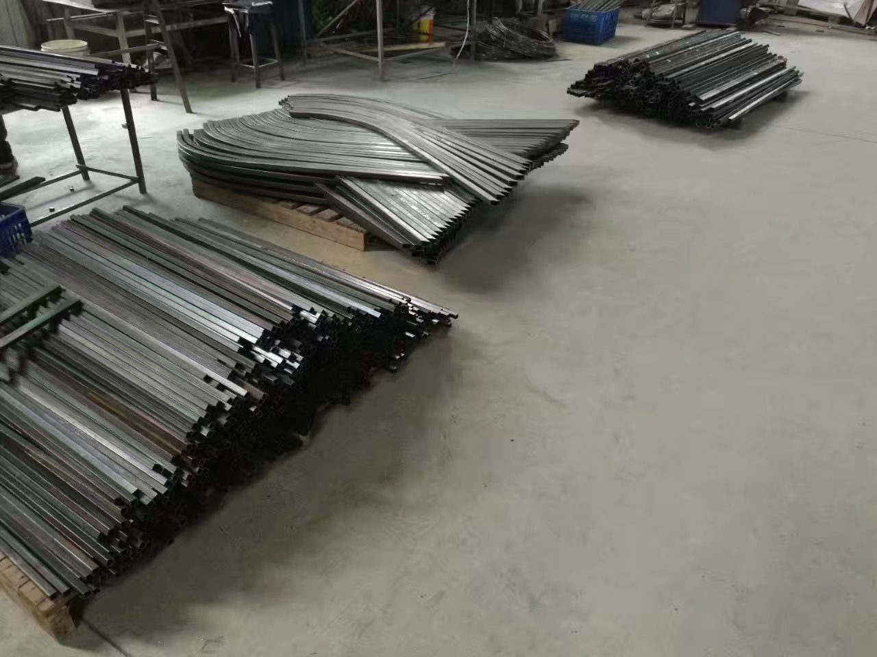 Bent and straight steel tube parts laid on the shop floor between forming operations