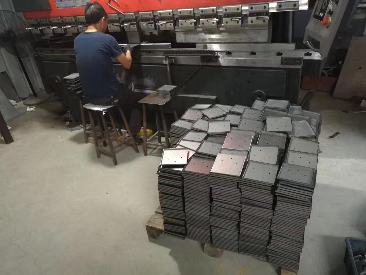 A press brake operator bending sheet-metal blanks in a specialist bending shop, a different trade from mold making