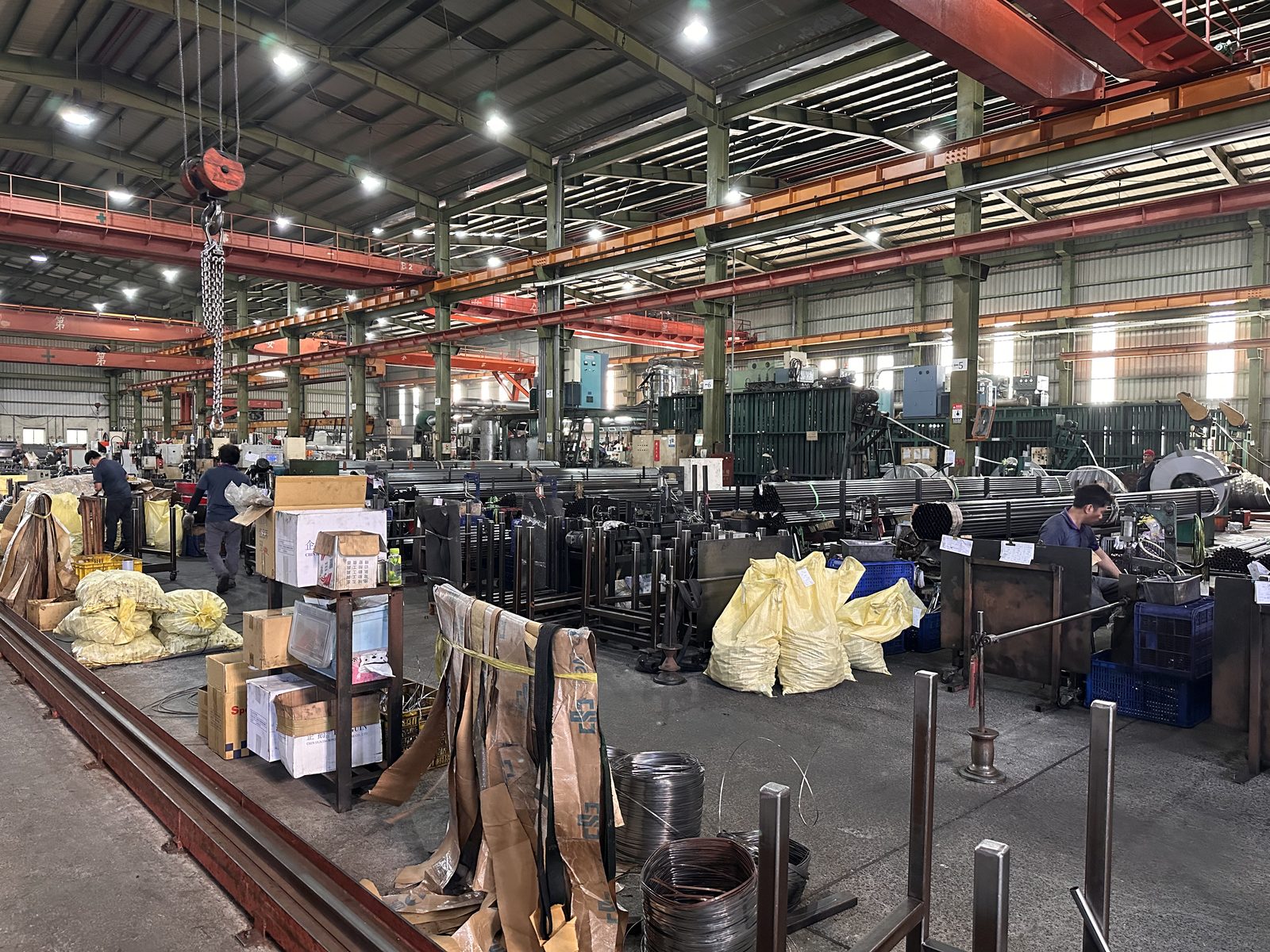 A long tube and wire fabrication shop floor with bending machines and coiled stock, one specialist trade