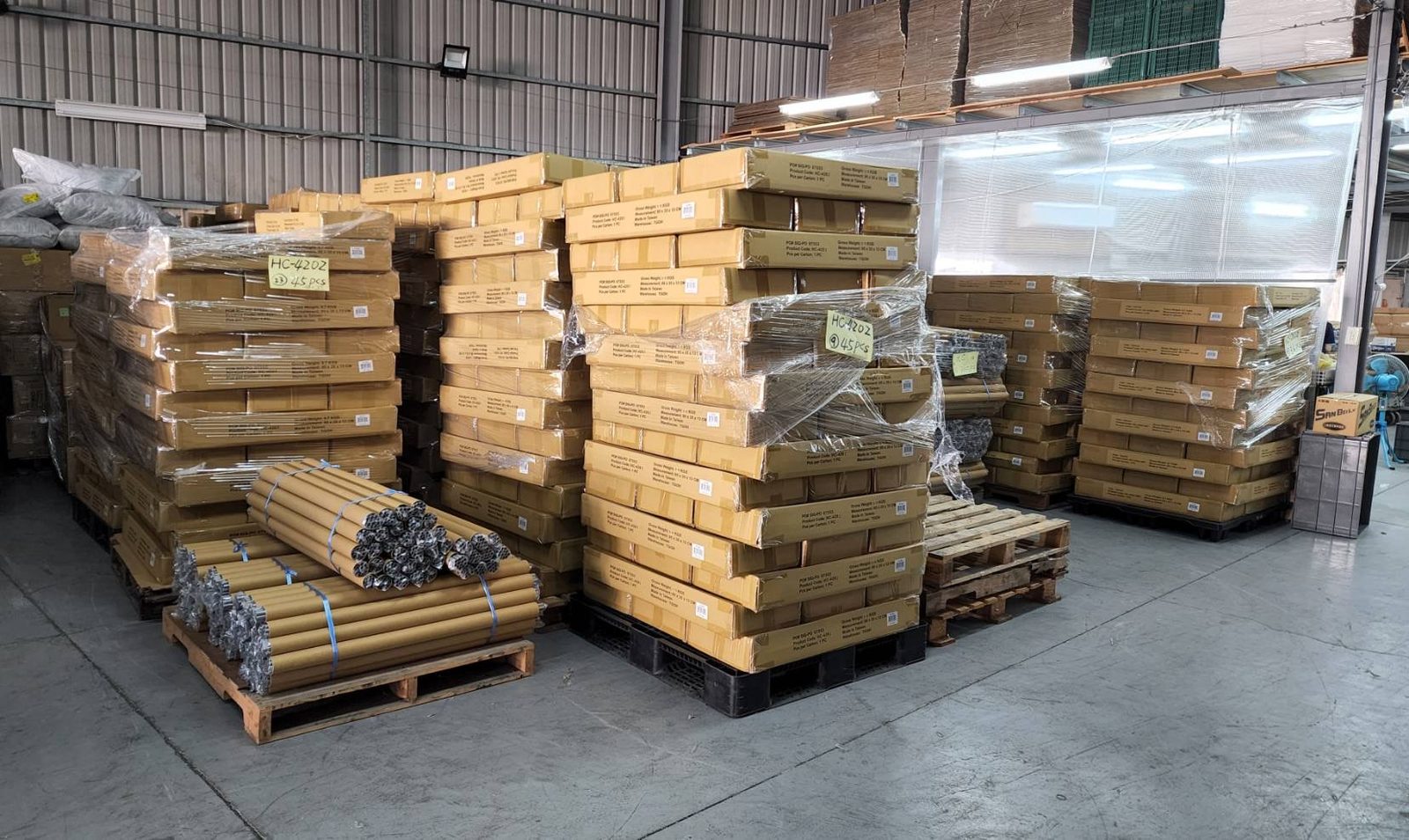 Palletized export cartons and strapped bundles of kraft tubes in a warehouse, marked by lot