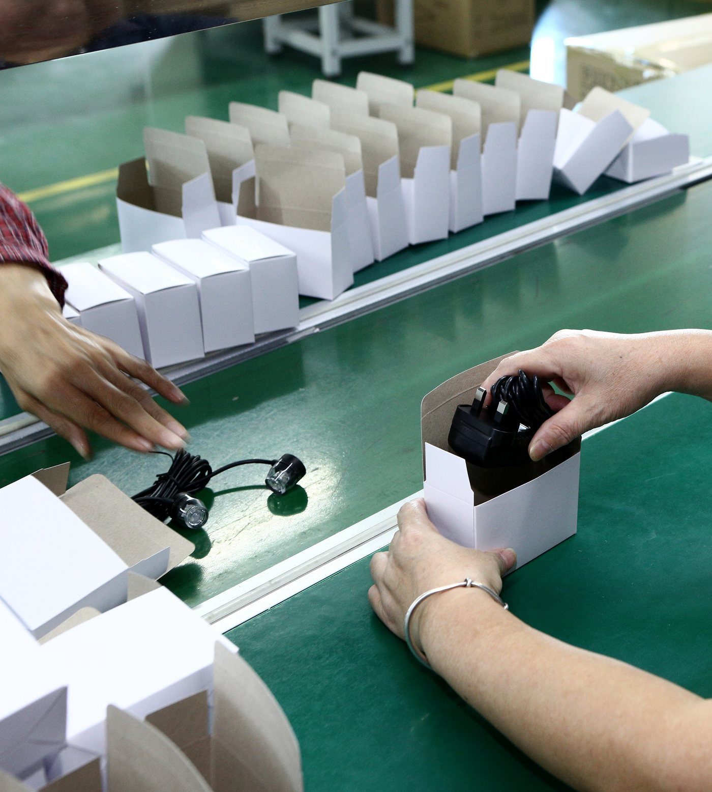 Hands boxing finished units on a packing line, the last point for a pre-shipment quality inspection