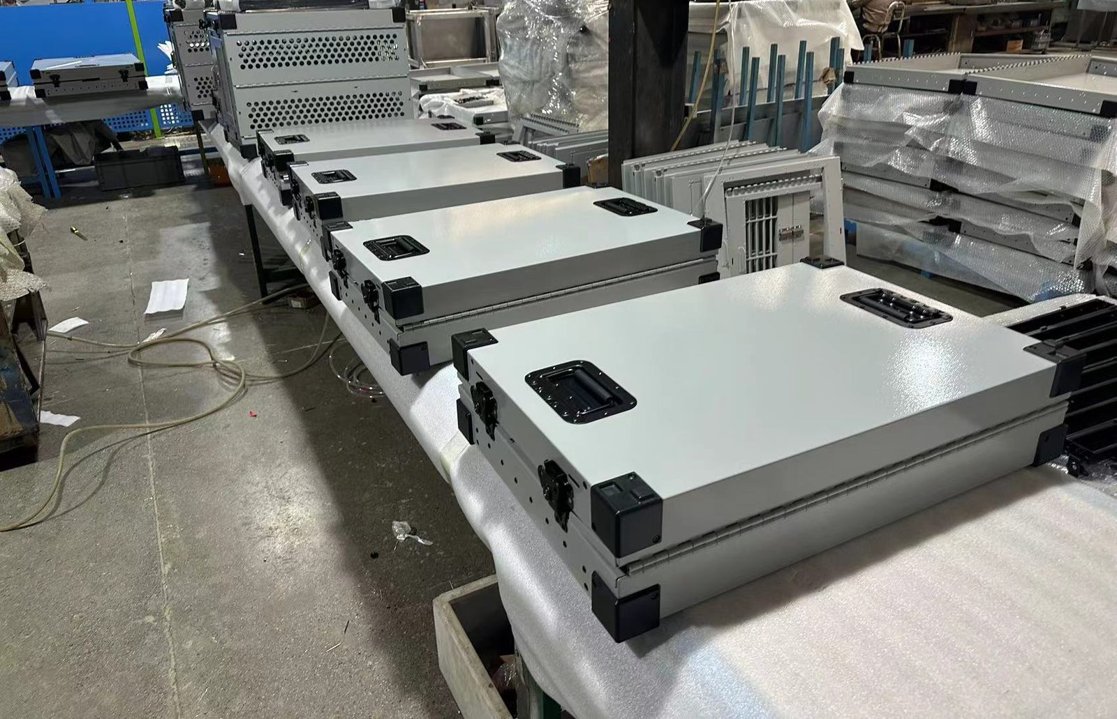 A production lot of assembled sheet-metal cases lined up on the line, checked against the golden sample
