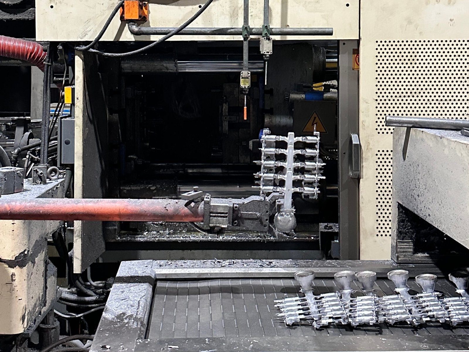 A die-casting cell with freshly ejected aluminum shots still on the runner in front of the die