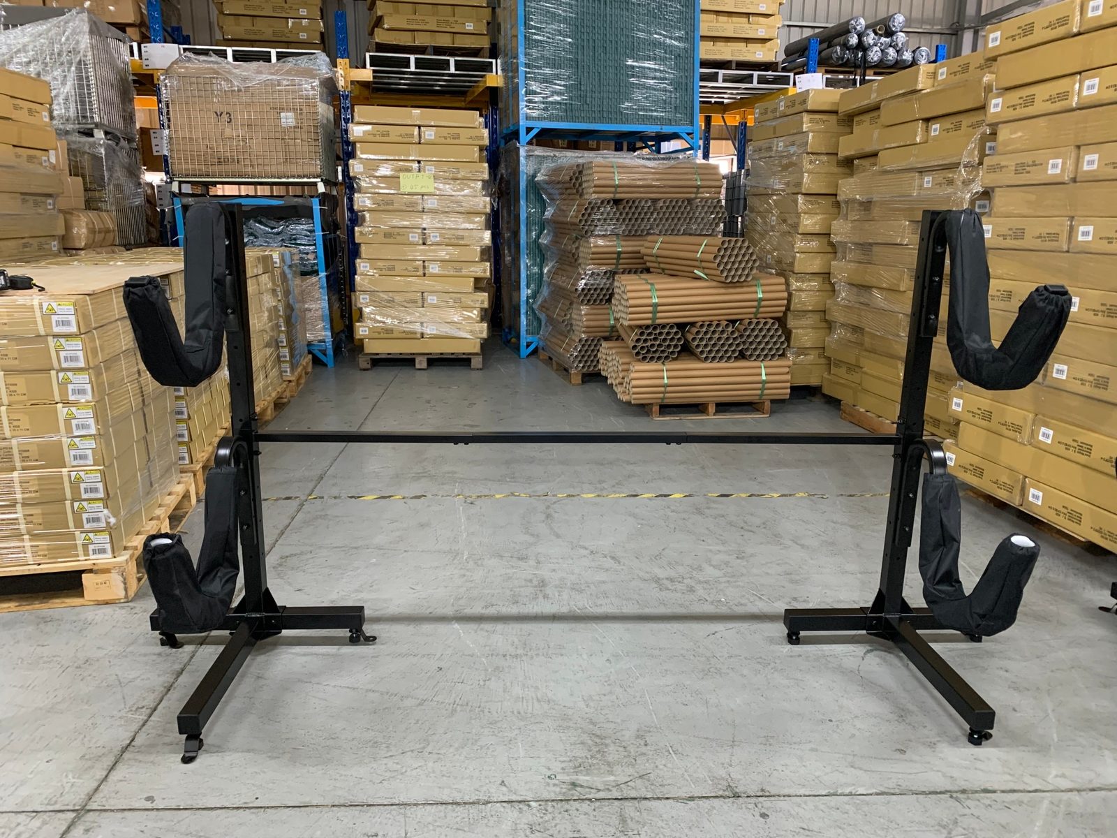 An assembled black steel rack with padded cradles standing in a warehouse aisle