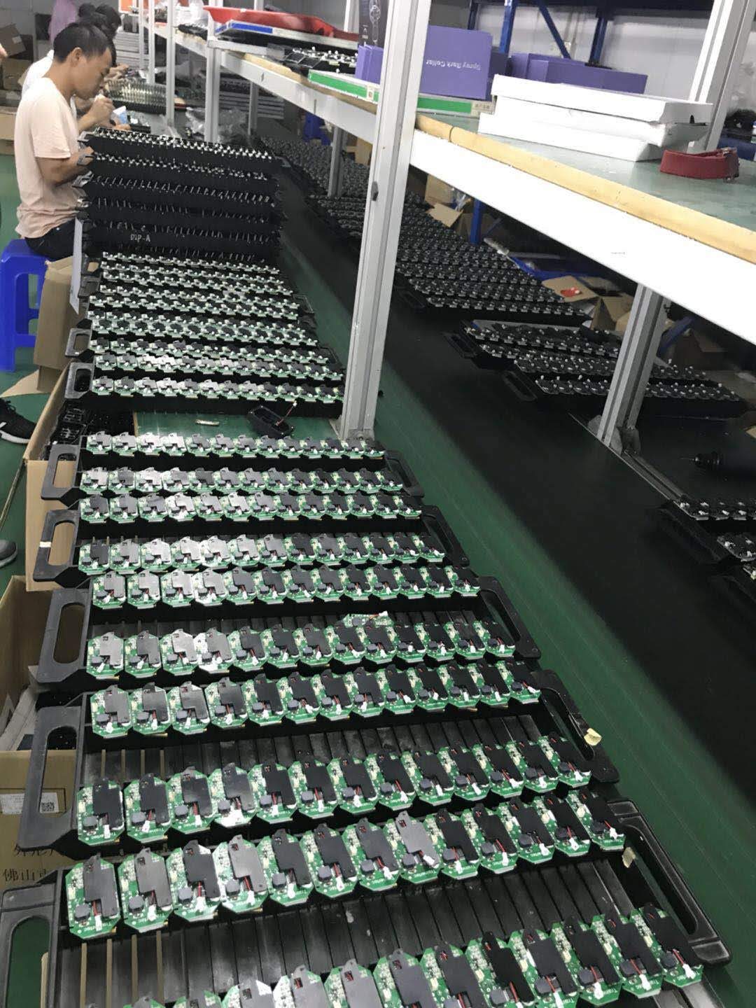 Rows of assembled green circuit boards standing in black ESD racks on an electronics line