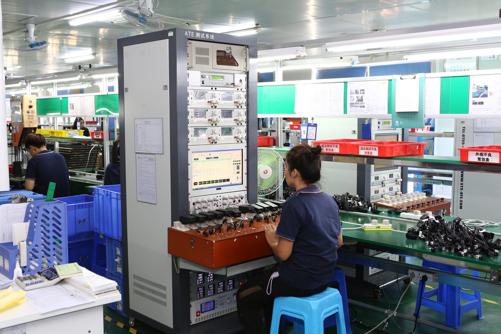 An operator at an automatic test equipment rack testing units on an electronics assembly line