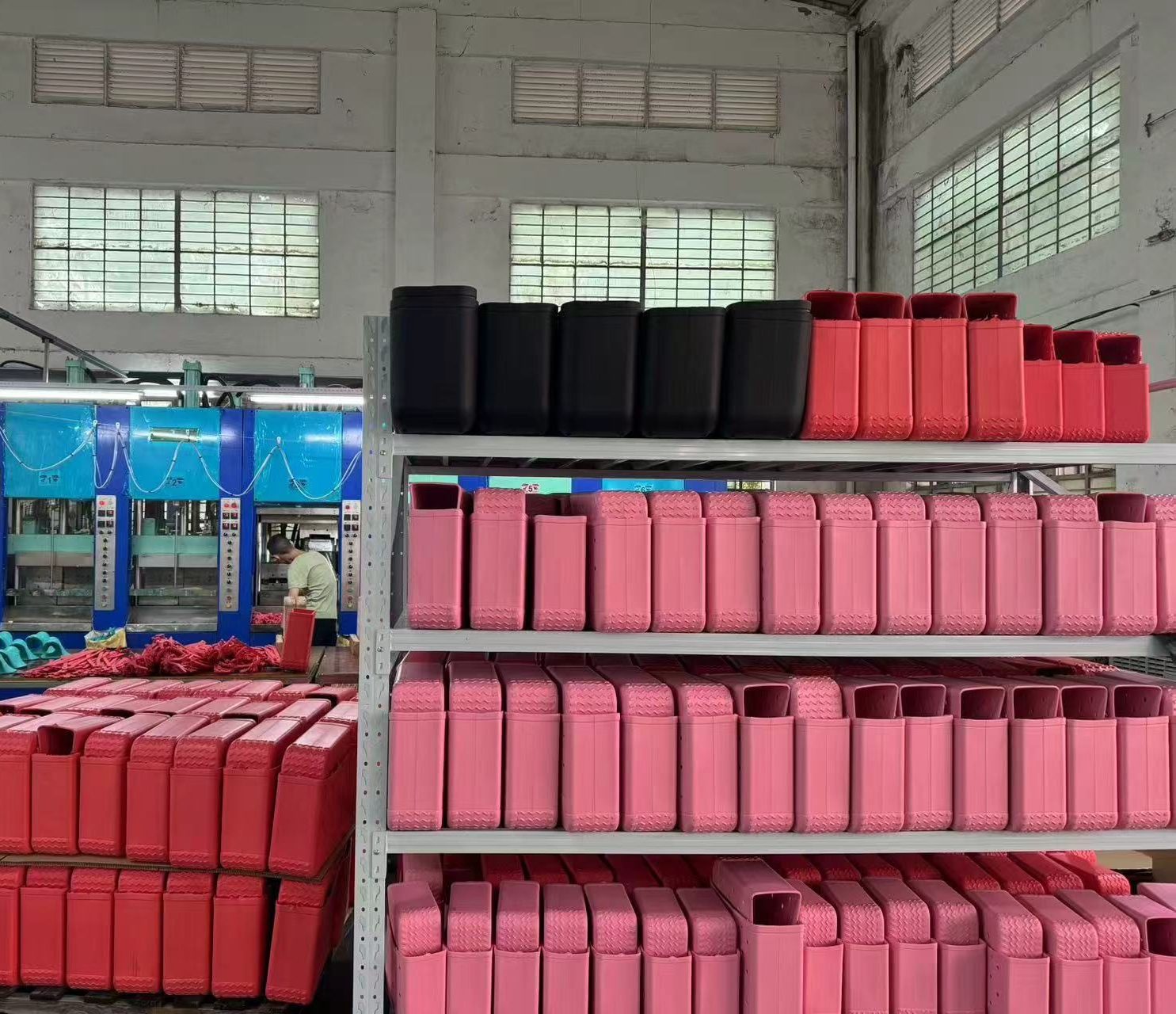 Racks of red, pink and black molded parts stacked beside the molding presses that made them