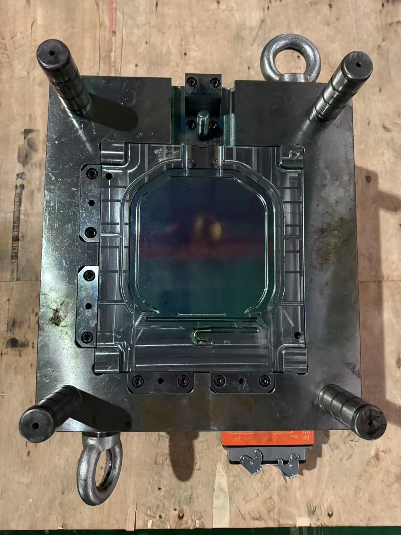 Top view of an open single-cavity injection mold with guide pillars and a lifting eye