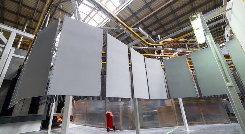 Large flat panels hang with an even gray film, ready to inspect