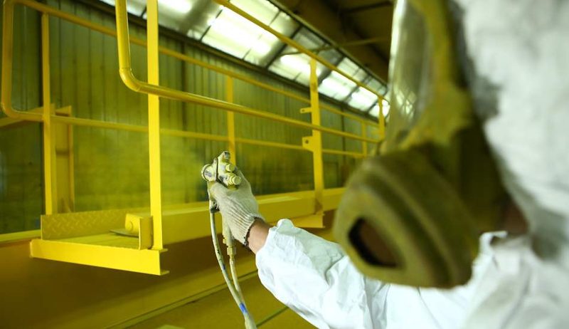 The gun and respirator in front of a yellow steel platform and rail.