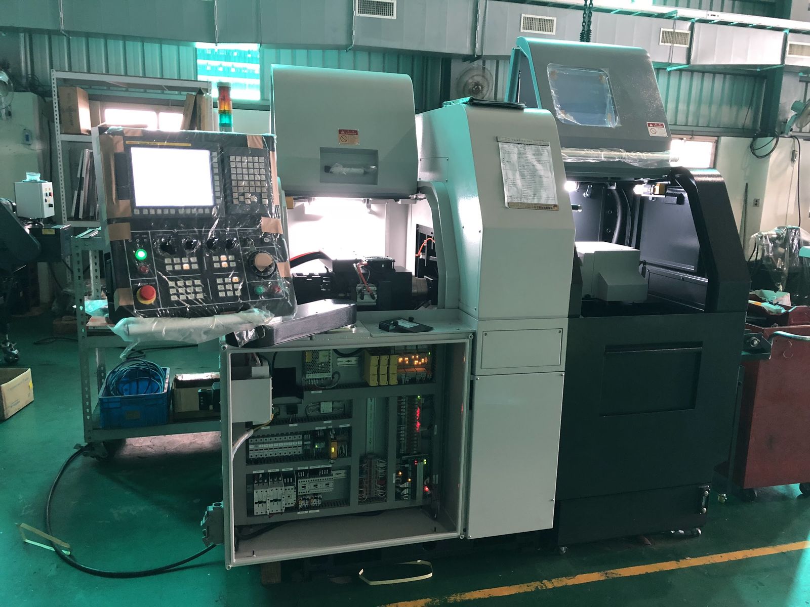 A CNC turning center and its control panel on a partner factory floor.
