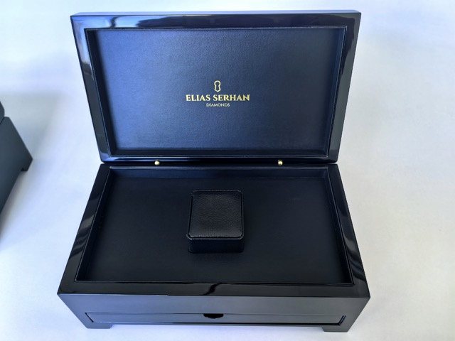 A black gloss presentation box with a satin lining and a fitted pillow