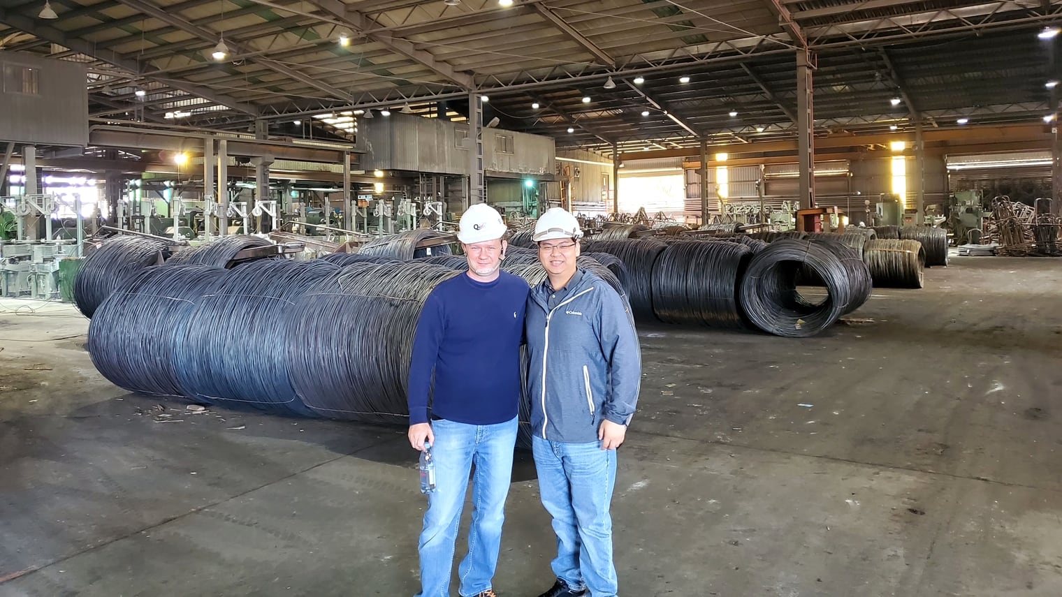 Jack Cheng, right, in a white hard hat beside a customer on the floor of a partner factory