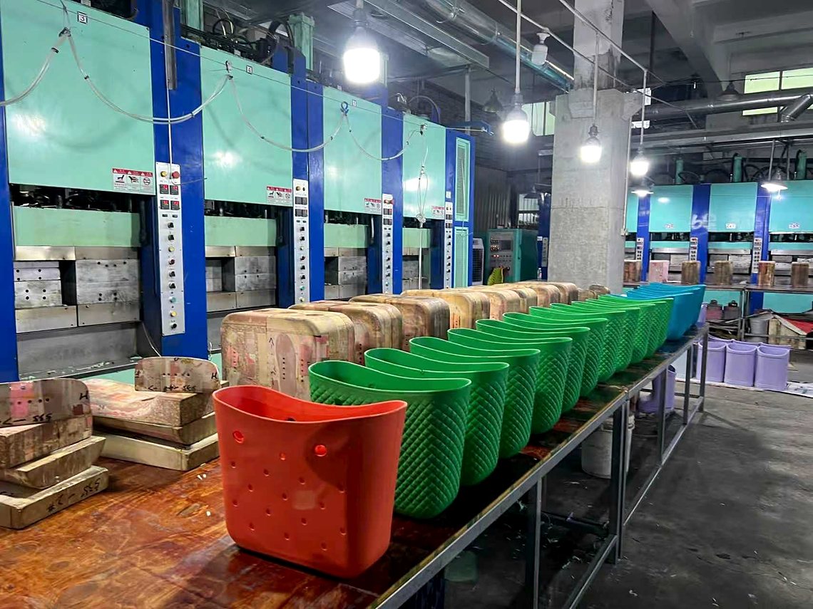 A row of molding presses with a line of fresh molded baskets on the bench