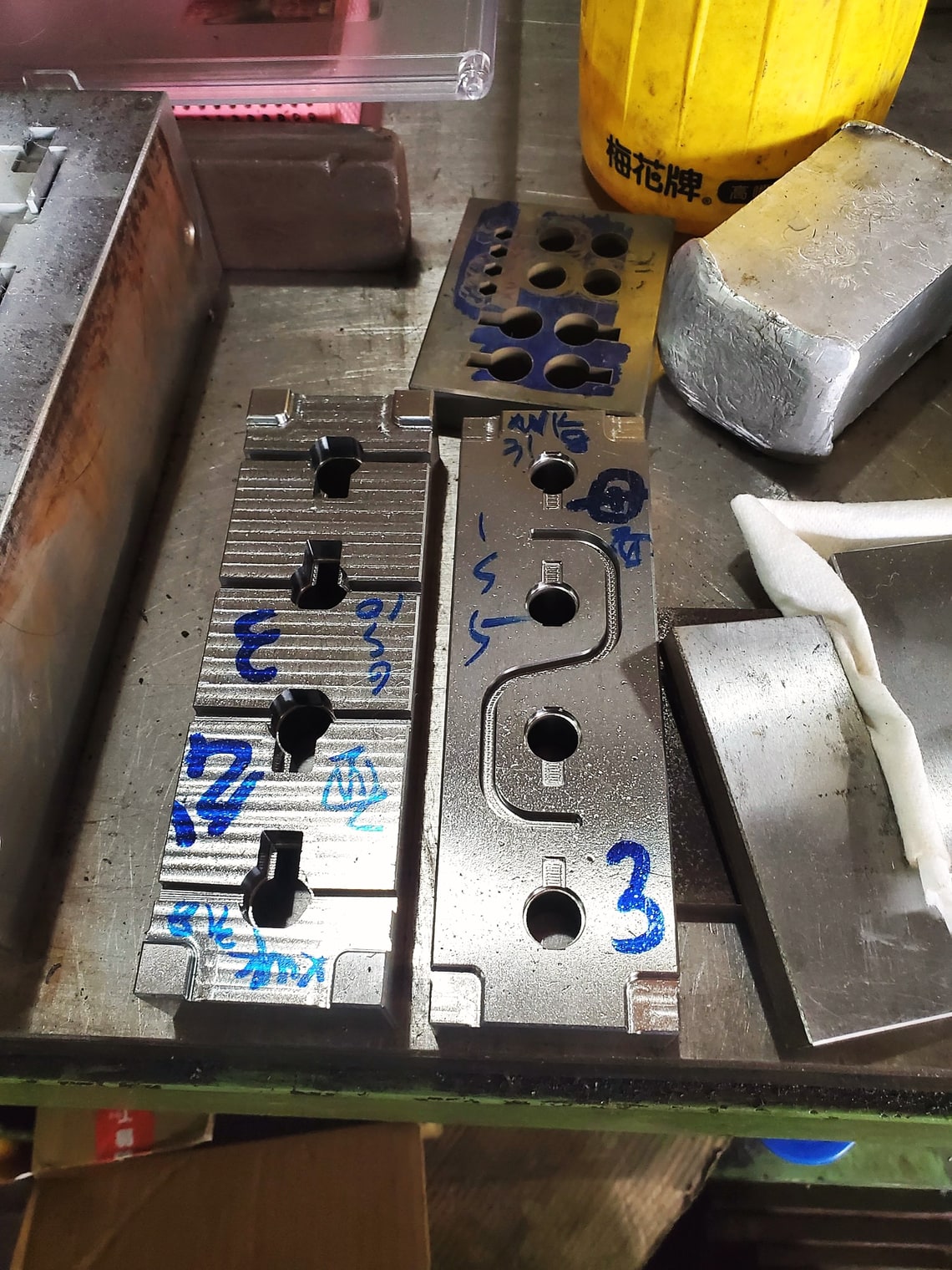 Steel cavity inserts marked up on a toolroom bench